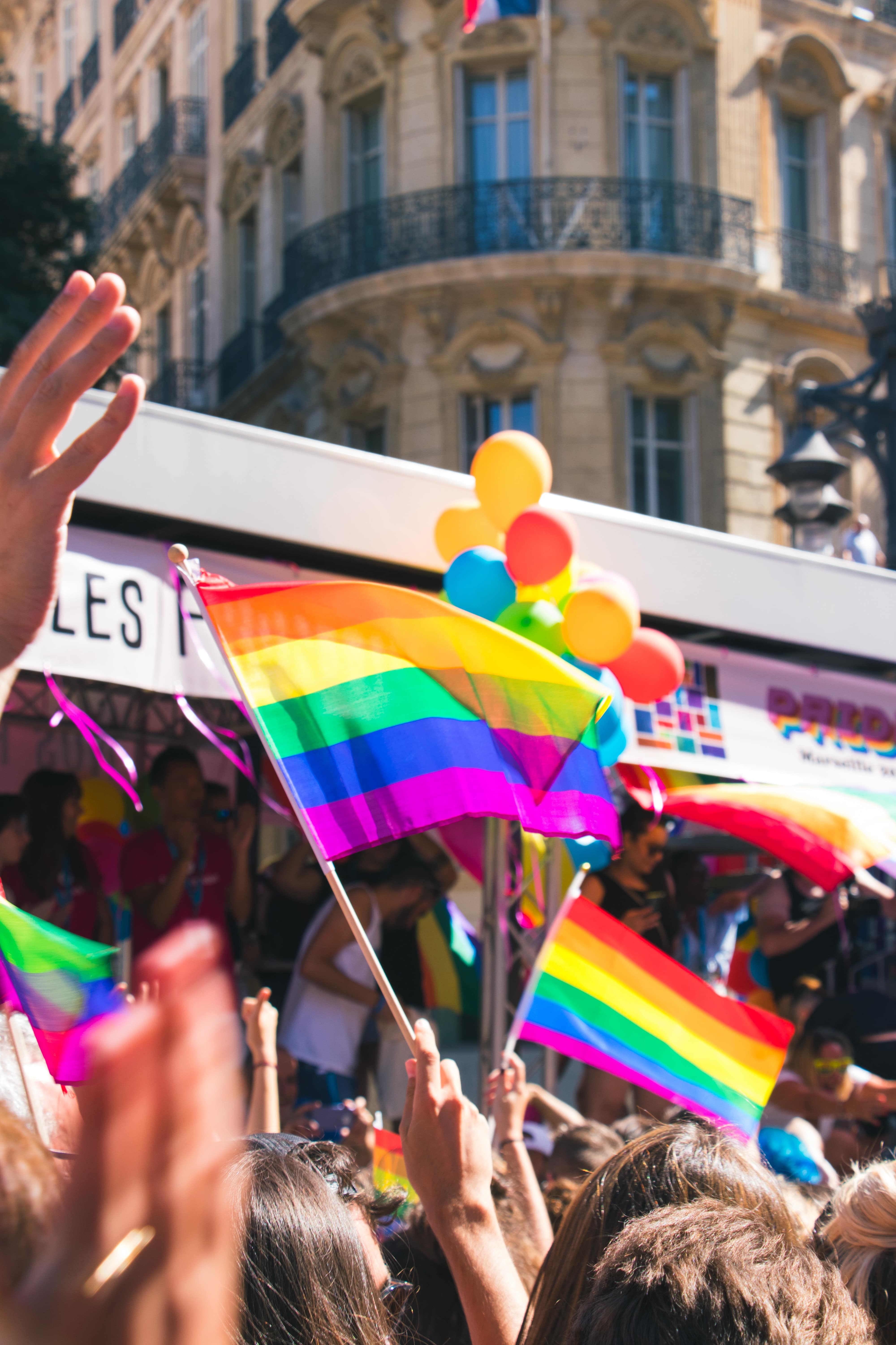 photo of people holding rainbow pride flags - real estate pride month